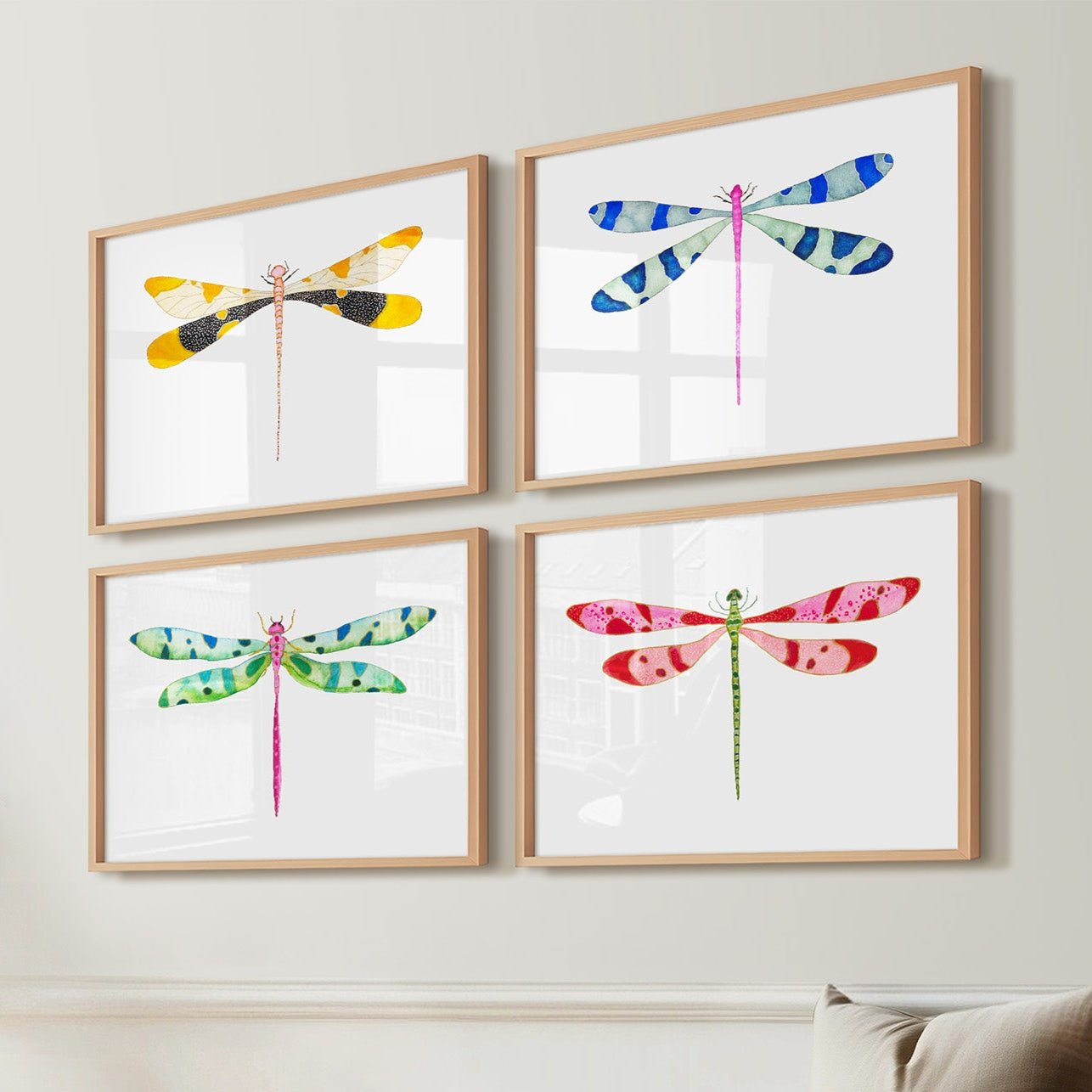Colorful dragonfly artworks on a wall above a wooden bench with a vase of dried flowers.
