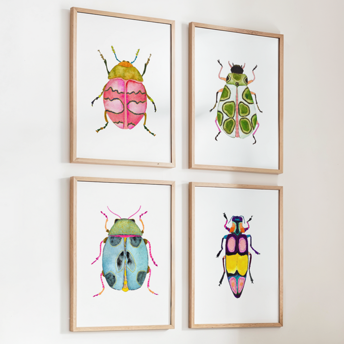 Four framed illustrations of colorful beetles on a wall above a crib.