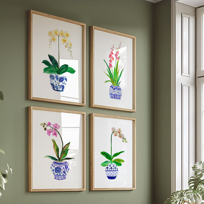 A set of four framed art prints featuring watercolor illustrations of orchids in various colors displayed on a wall.
