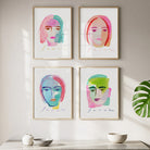 Four colorful face portraits on a wall above a concrete shelf with decorative items.