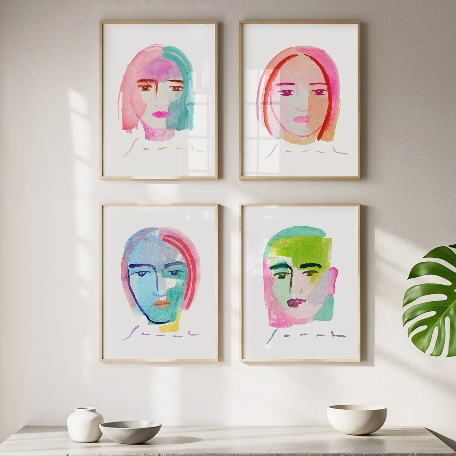 Four colorful face portraits on a wall above a concrete shelf with decorative items.
